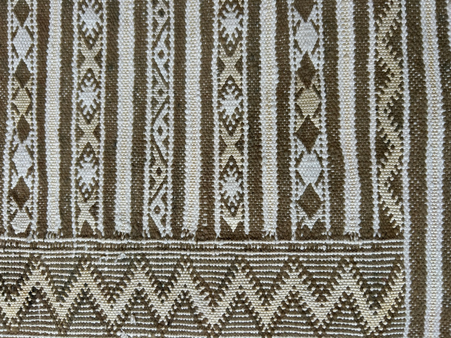 zoom sur les détails du tapis fin artisanal cilié, motifs kaki jaune et blanc