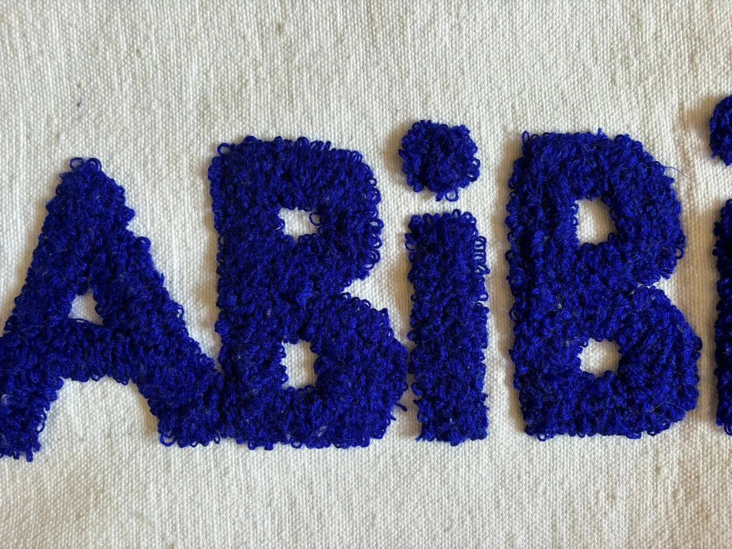 zoom sur la laine blanche en fond, et le motif bouclette bleu roi