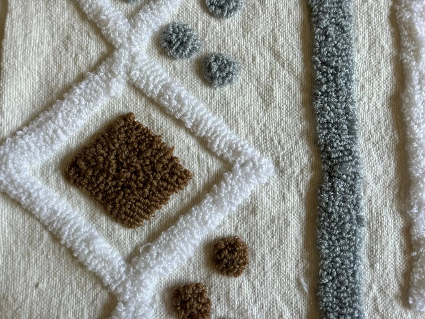 zoom sur qualité de la laine blanche, les motifs blancs, marron et gris