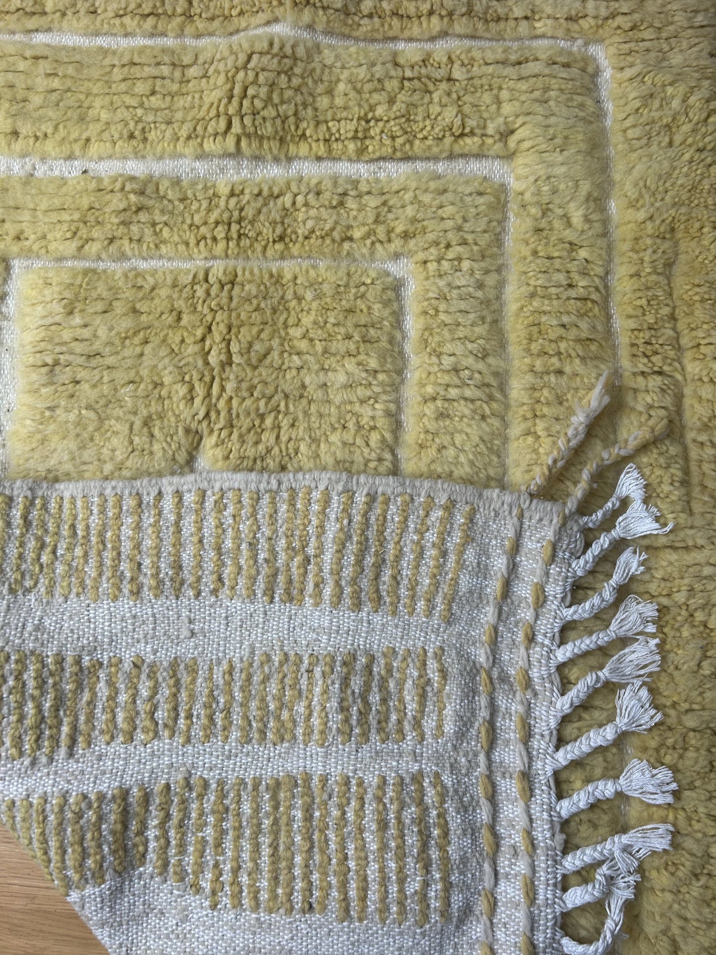 zoom sur l'arrière du tapis et sur le motif et sa laine jaune