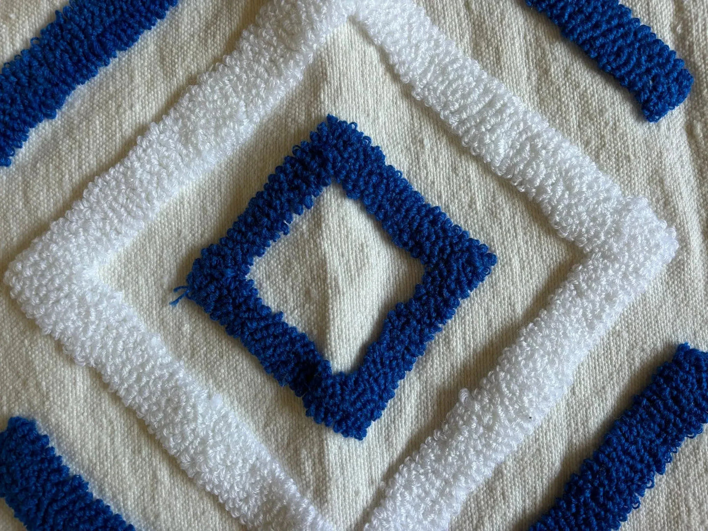 zoom sur le motif graphique laine de fond blanche, motif graphique blanc et bleu