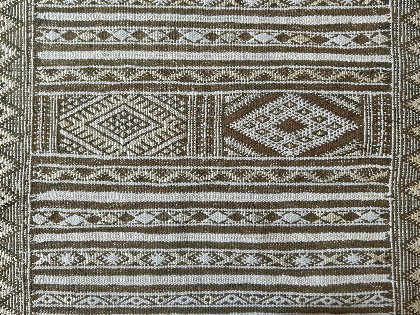 zoom sur les détails des motifs du tapis fin marocain Hanbel aux motifs kaki, blanc et jaune 