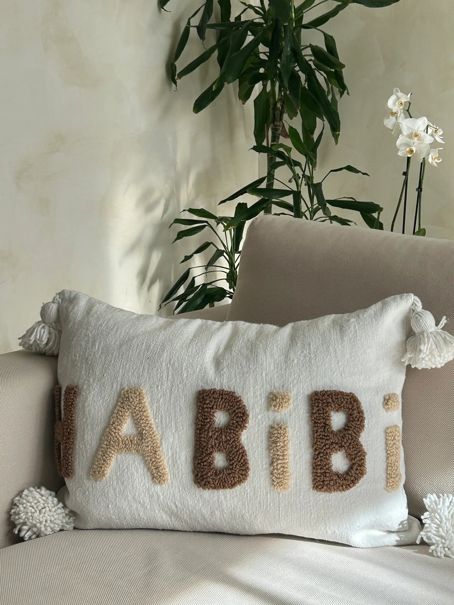 housse de coussin en laine blanche artisanale et motif brodé en beige et marron, avec pompons