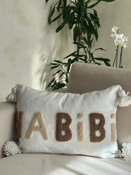 housse de coussin en laine blanche artisanale et motif brodé en beige et marron, avec pompons
