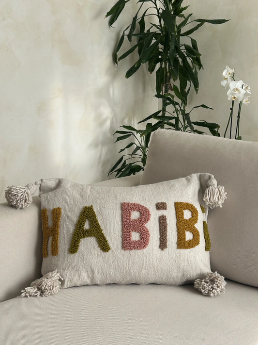 housse de coussin artisanale en laine grise avec pompons et motifs Habibi en orange, vert, vieux rose et marron 