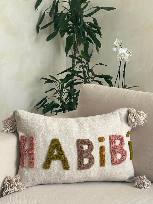 housse de coussin en laine artisanale grise avec pompons et motif rose; vert, marron et orange