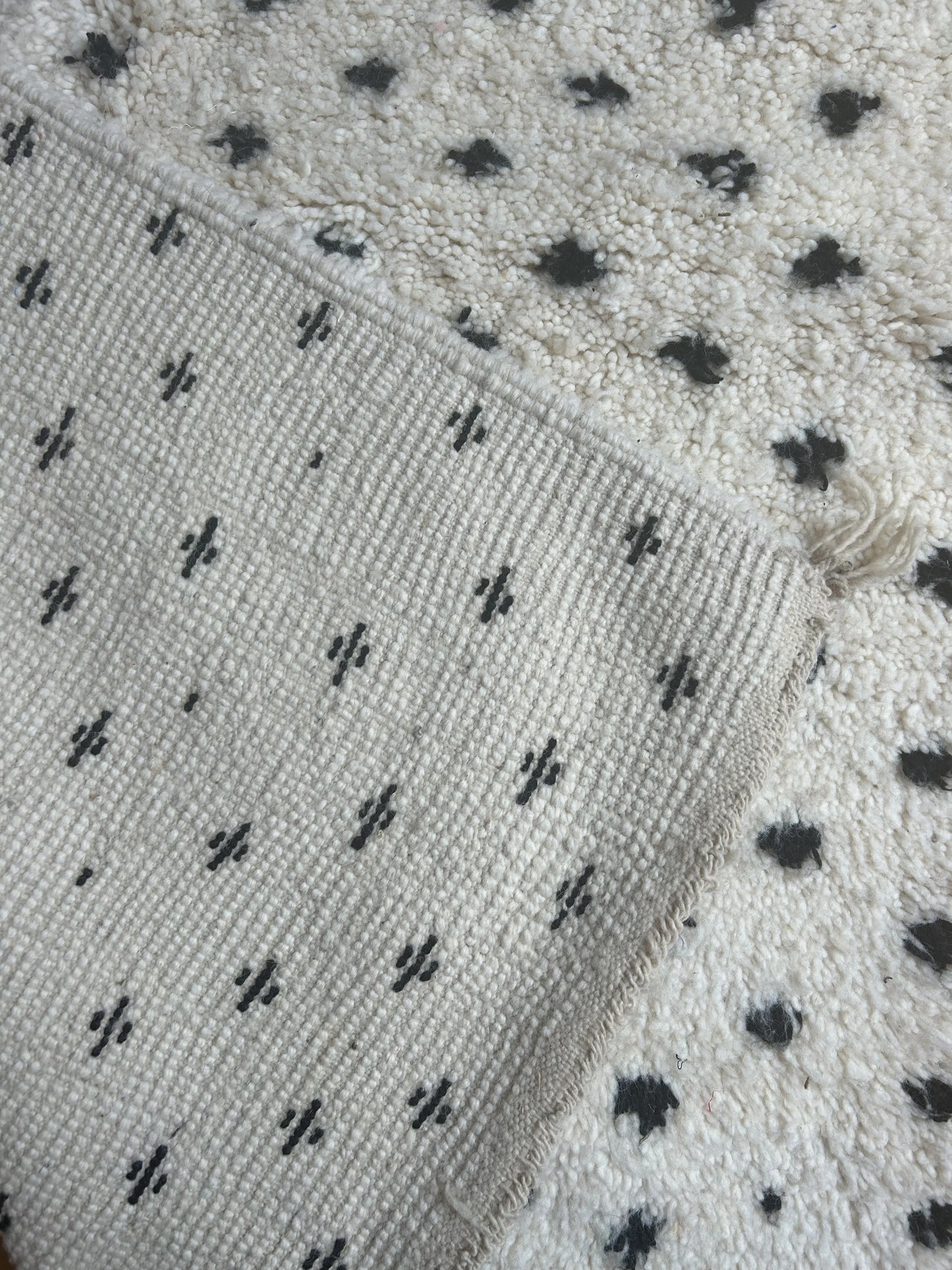 zoom sur le motif pois noir sur fond blanc du tapis et sur l'arriere