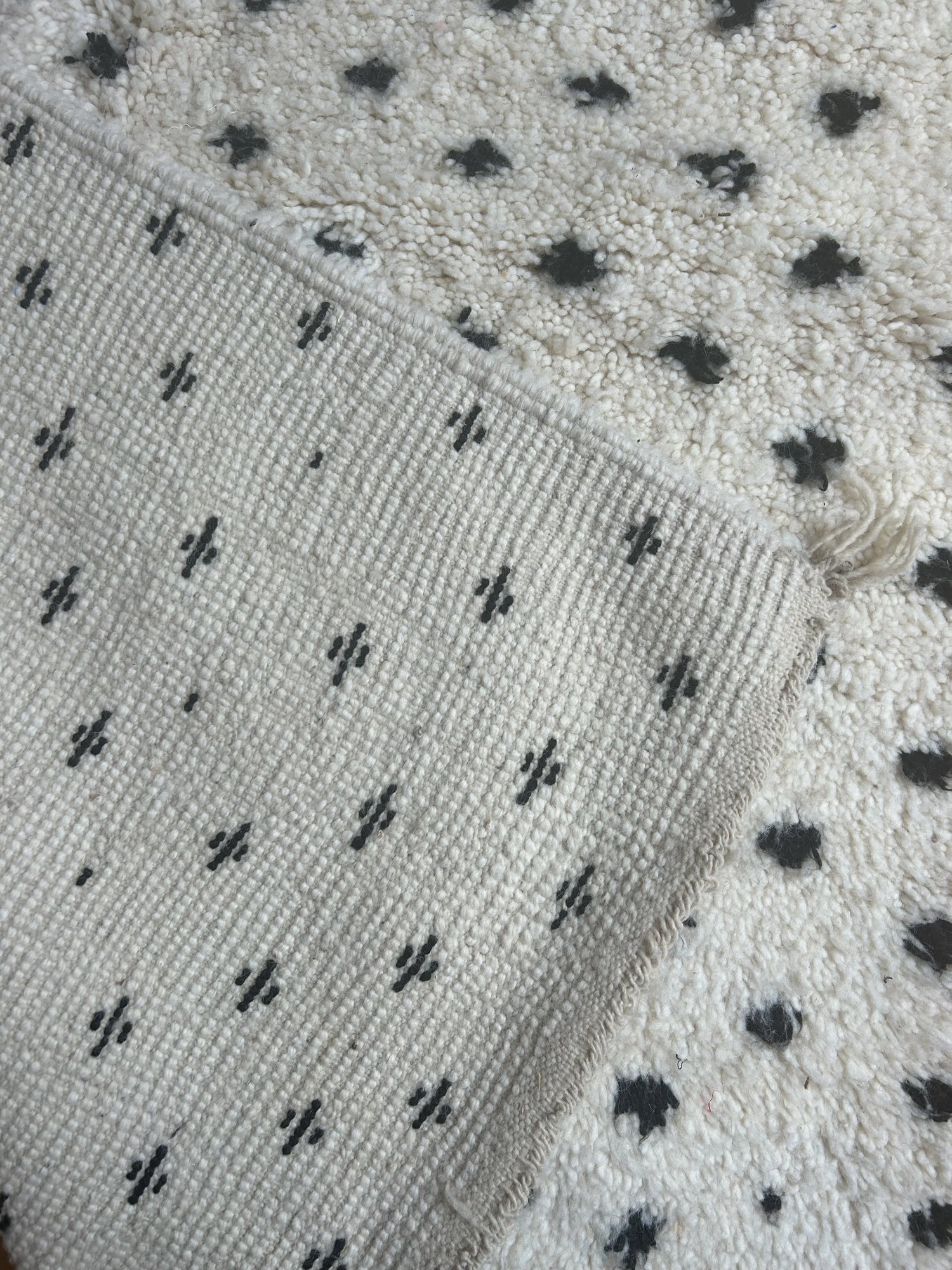 zoom sur le motif pois noir sur fond blanc du tapis et sur l'arriere