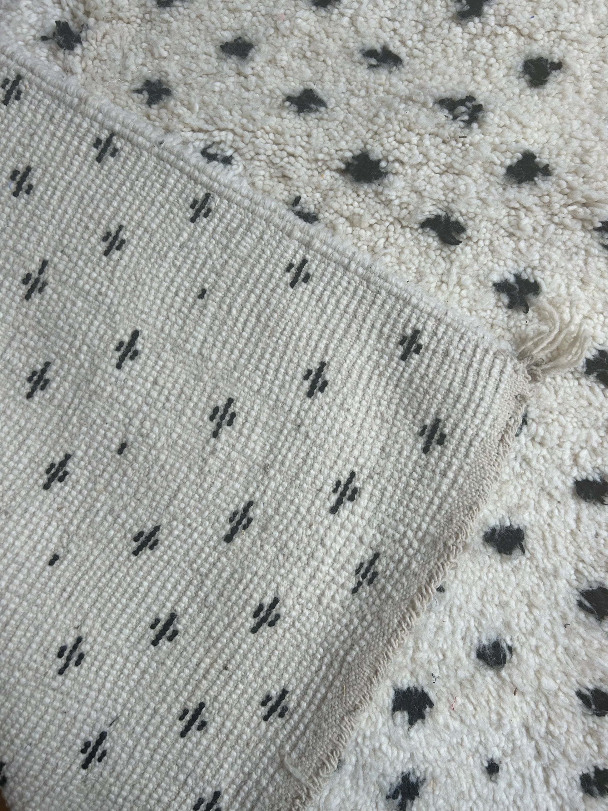 zoom sur le motif pois noir sur fond blanc du tapis et sur l'arriere